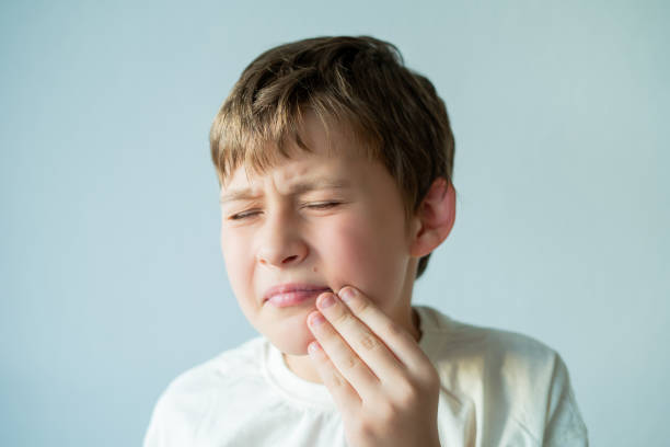 istock Toothache. 10 year old boy holds his face with his hand. Home. 2171045154