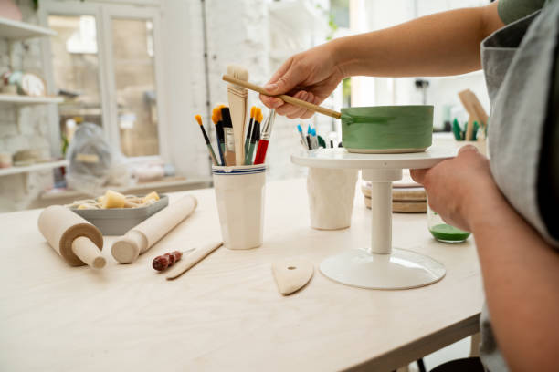 istock Using a brush to paint a ceramics bowl. Learning how to paint a handmade pottery project. Girl is decorating a clay product with bright green color. 2171045988