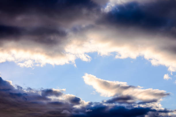 The sky is cloudy and the sun is shining through the clouds. The birds are flying in the sky
