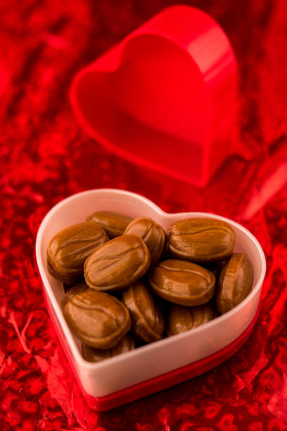 High angle view of some candies in red heart shaped pot on bright red background
