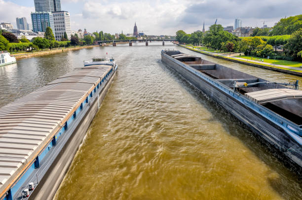 Frankfurt, Germany - July 29, 2024: The view of two barges passing under a bridge over the River Main in Frankfurt