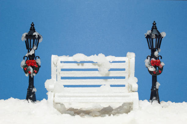 Christmas Scene with White Bench Covered with Artificial Snow and Black Light Poles Decorated with Wreaths in a Miniature Winterscape