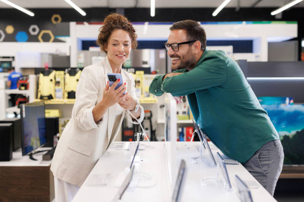 istock A cheerful couple looking at smart phone in the electronics store 2171051964