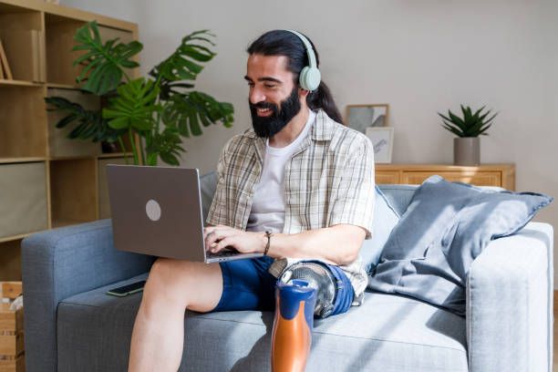 istock Amputee man with prosthetic leg working on laptop at home 2171055854