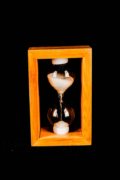 A wooden box with a glass top and a sand timer inside. The box is empty and the timer is not in use