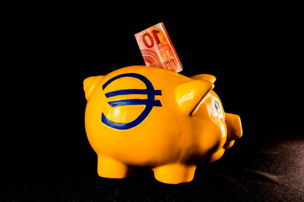 A piggy bank with a 10 euro bill inside. The piggy bank is yellow and has a blue stripe
