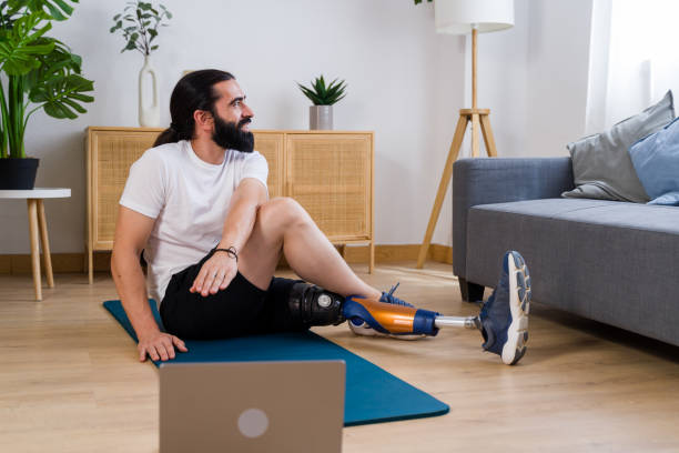 istock Young man with prosthetic leg doing stretching exercise following online class at home 2171056344