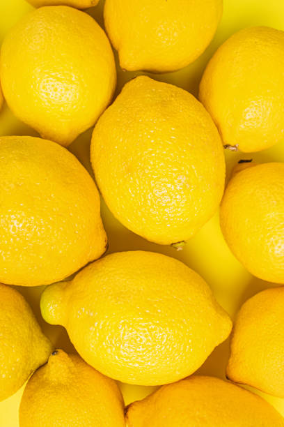 istock Close-up view of fresh lemons arranged on a vibrant yellow surface 2171058734