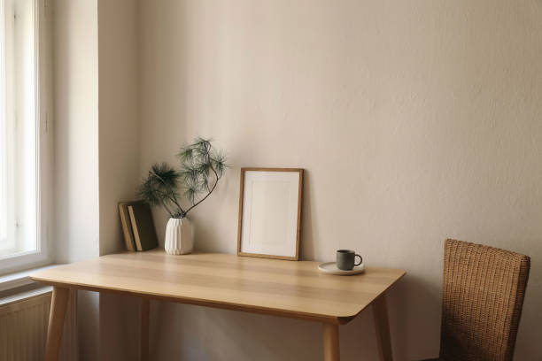 istock Cozy Christmas interior. Minimal winter home composition. Blank vertical wooden picture frame mockup, cup of coffee on table near window. Pine tree branches, white vase. Beige wall background 2171059567