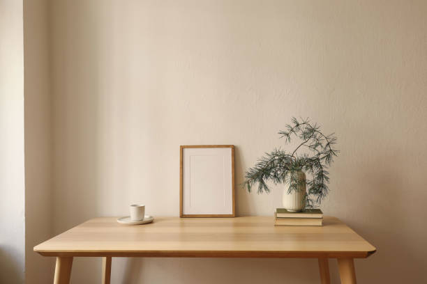 istock Warm Christmas Scandinavian interior. Minimal winter artistic composition. Blank vertical wooden picture frame mockup, cup of coffee on table. Pine tree branches, white vase. Beige wall background 2171059590
