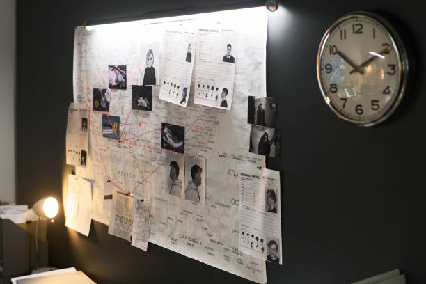 Investigating Crime Scene Evidence in Dim Room Researcher examining crime scene photos and related documents pinned on office board creating crime investigation layout with multiple connections and leads displayed under dim light spy games stock pictures, royalty-free photos & images
