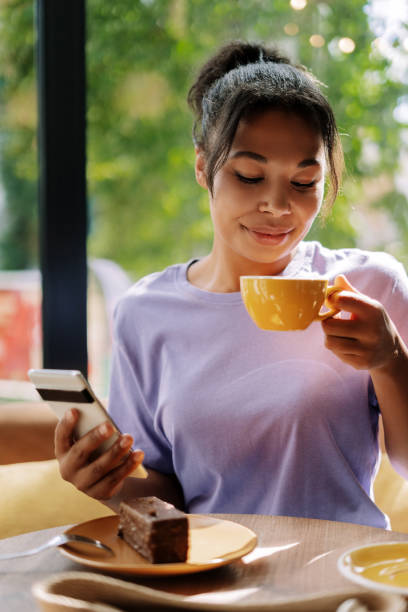 istock African American woman enjoying coffee and dessert while using smartphone in cafe 2171063820