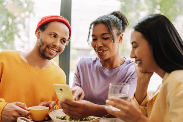 istock Diverse group of friends sharing a fun moment while looking at smartphone in cafe 2171063847