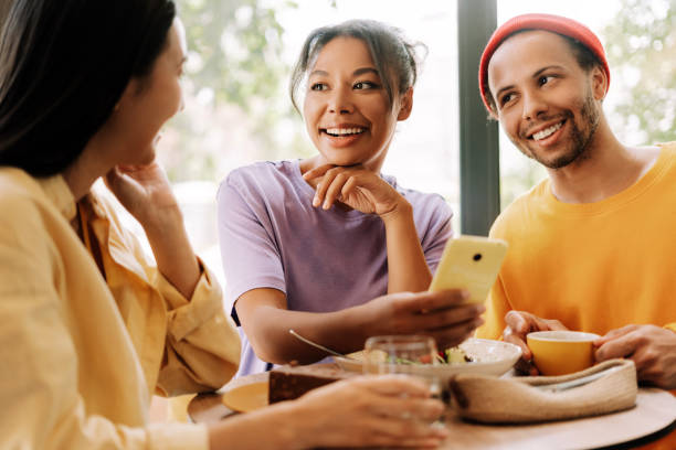 istock Happy diverse friends sharing funny content on mobile phone while having lunch together in cafe 2171063857