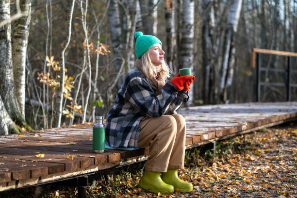 istock Time alone. Relaxed middle aged woman enjoy calm weekend in fall park meditative drinks thermos tea. 2171067898