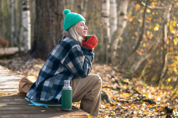 istock Time alone. Relaxed middle aged woman enjoy calm weekend in fall park meditative drinks thermos tea. 2171067905