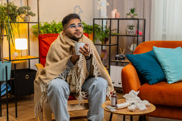 istock Sick Indian man wrapped in plaid sit alone shivering trembling from cold on chair drinking hot tea 2171075923