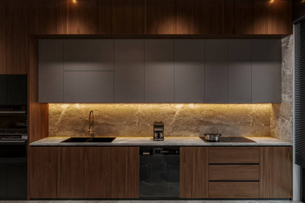 istock Compact kitchen features sleek wooden and black cabinets. The backsplash and countertop match the cabinet's wooden finish. 2171088019