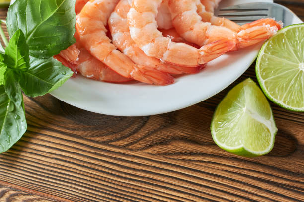 istock Shrimp on a white plate with lime and basil, wooden background. 2171089308