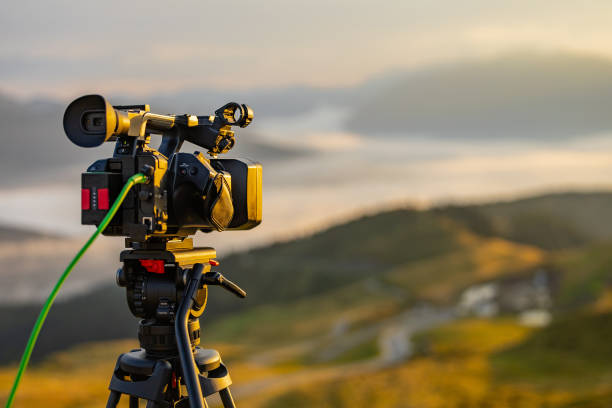 istock Modern video camera filming on a tripod a beautiful morning panorama. Typical work for a videographer in the morning, handheld camera with sdi signal cable in the back 2171091175