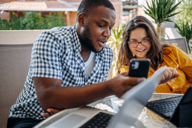istock Young couple enjoying spending time together at home sitting on balcony and using different wireless technology while looking at mobile phone 2171093061