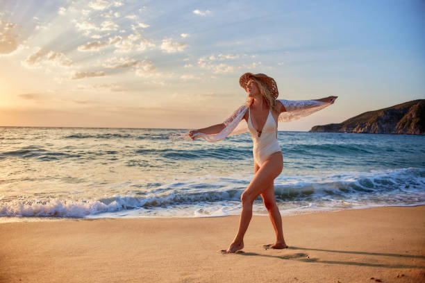 Beautiful woman running inside water on the beach at sunset.