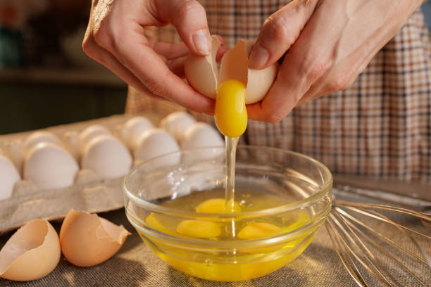 istock A person cracking an egg into a glass bowl, with several eggs in an egg carton in the background 2171094035
