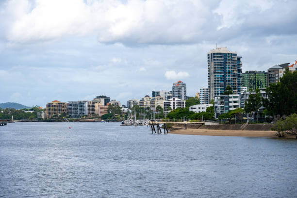 A residential area seen behind the Brisbane River in Brisbane, Australia, a cloudy day in the summer.