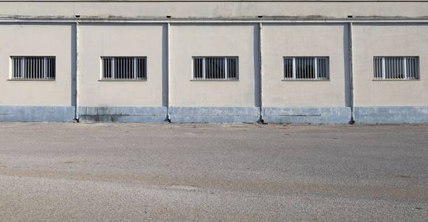 istock Cream colored facade with large barred windows at the roadside. Street in front. 2171099450