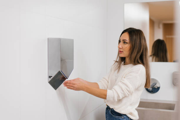 istock Caucasian woman dries her hands with hot water using a dryer 2171099939