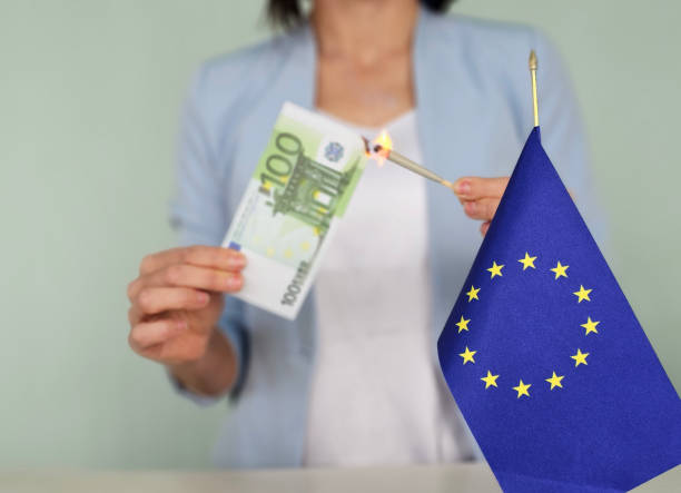 Person holds a 100 euro note while lighting it with a match, standing beside the European Union flag concept