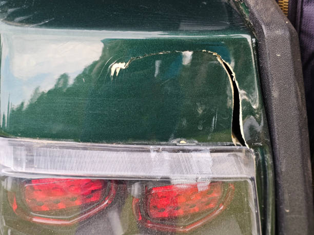 Green car has noticeable paint damage and a crack near tail light