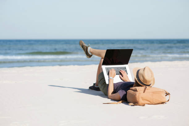 istock Young woman using laptop on a beach 2171103895