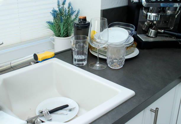istock White ceramic kitchen sink and dirty unwashed dishes on dark kitchen table 2171103971