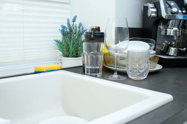istock White ceramic kitchen sink and dirty unwashed dishes on dark kitchen table 2171103976