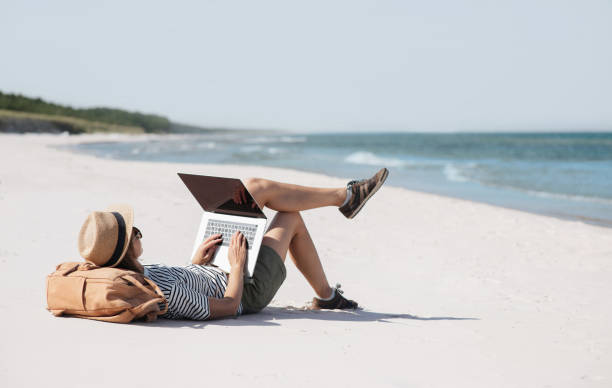 istock Young woman using laptop on a beach 2171105579