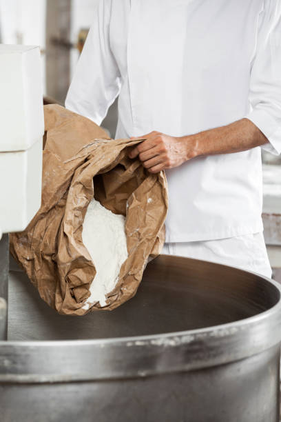 istock Midsection Of Mature Baker Pouring Flour In Kneading Machine 2171105854