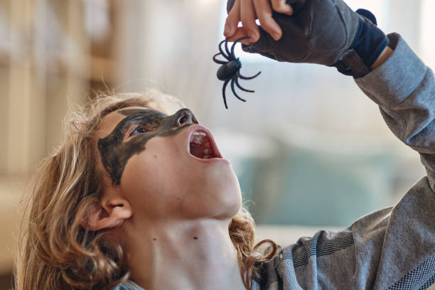 istock Beautiful boy on Halloween day dressed as a hero eating spider 2171106102