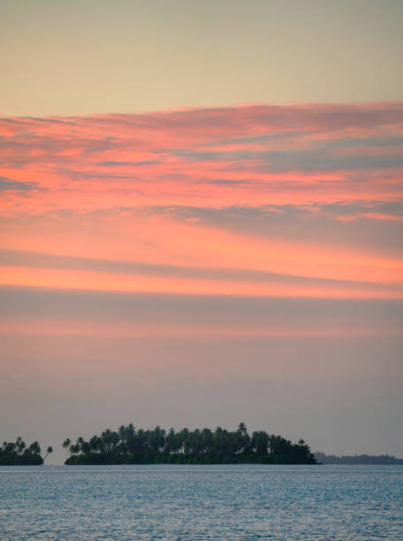 A spectacular sunset in the Maldives and a distant island is silhouetted against the glorious sunset.