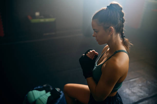 istock Young woman, wrapping a bandage around her wrist before a kickbox practice 2171113568