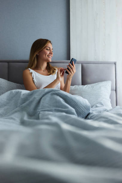 istock Happy woman using mobile phone during morning in bedroom. 2171114608