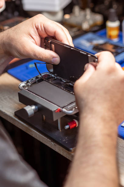 istock A technician carefully disassembles a smartphone to replace its battery in a well-equipped repair shop 2171118952