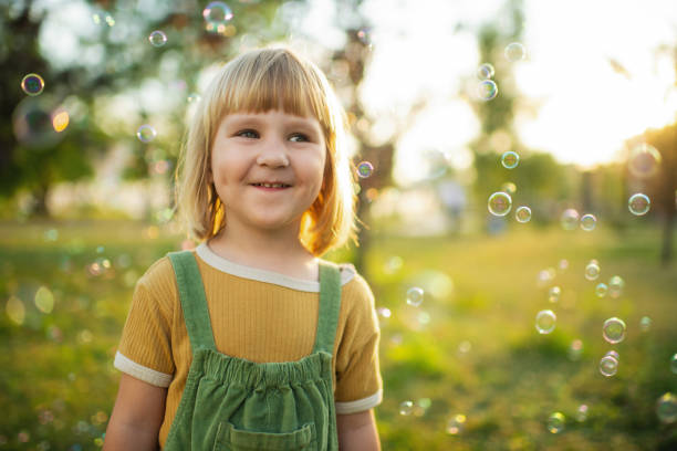 istock Little girl playing  in a park with soap bubbles 2171120238