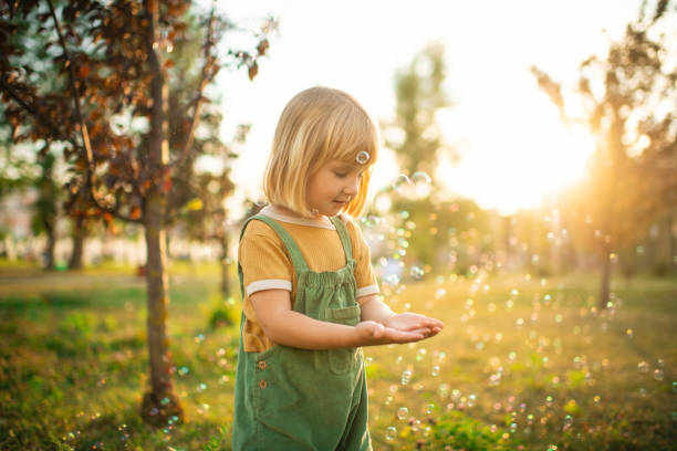 istock Little girl playing  in a park with soap bubbles 2171120258