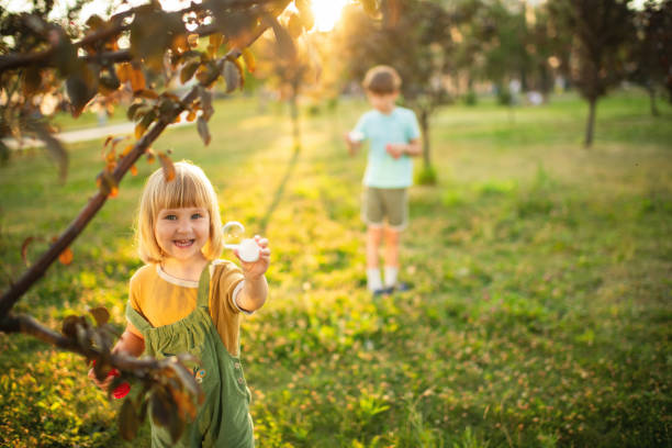 Boy and girl playing  in a park and blowing bubbles