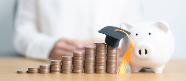 istock Money saving for Education, Scholarship, Student loan and debt and study future plan concept. Coins stack growing up with piggy and graduation hat on table 2171121266