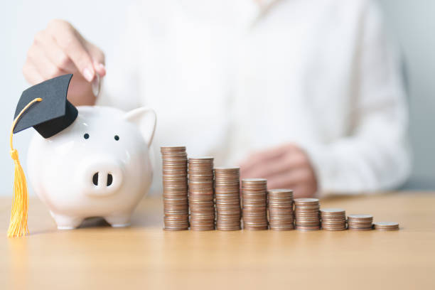 istock Money saving for Education, Scholarship, Student loan and debt and study future plan concept. Coins stack growing up with piggy and graduation hat on table 2171121267