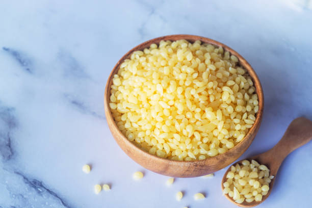 istock Candelilla wax in wooden bowl on white marble background 2171123621