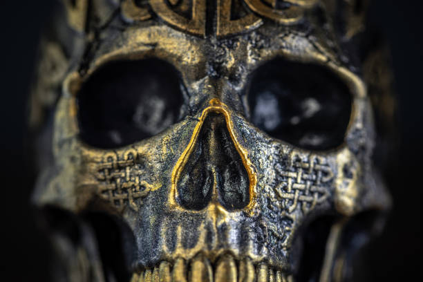 The skull is a symbol with deep roots in esoteric practices, representing mortality and transformation. In some cultures, it is believed to have protective powers or be used in rituals. Dark metallic and golden colours