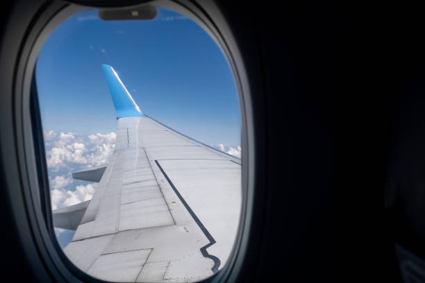 istock View of airplane wing and sky with clouds from a passenger window, 2171128944